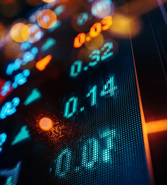 Gros plan sur un écran boursier affichant des chiffres lumineux avec un effet de flou bokeh.