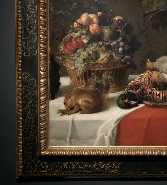 Peinture classique d'une nature morte avec fruits, gibier et un petit écureuil dans un cadre doré.